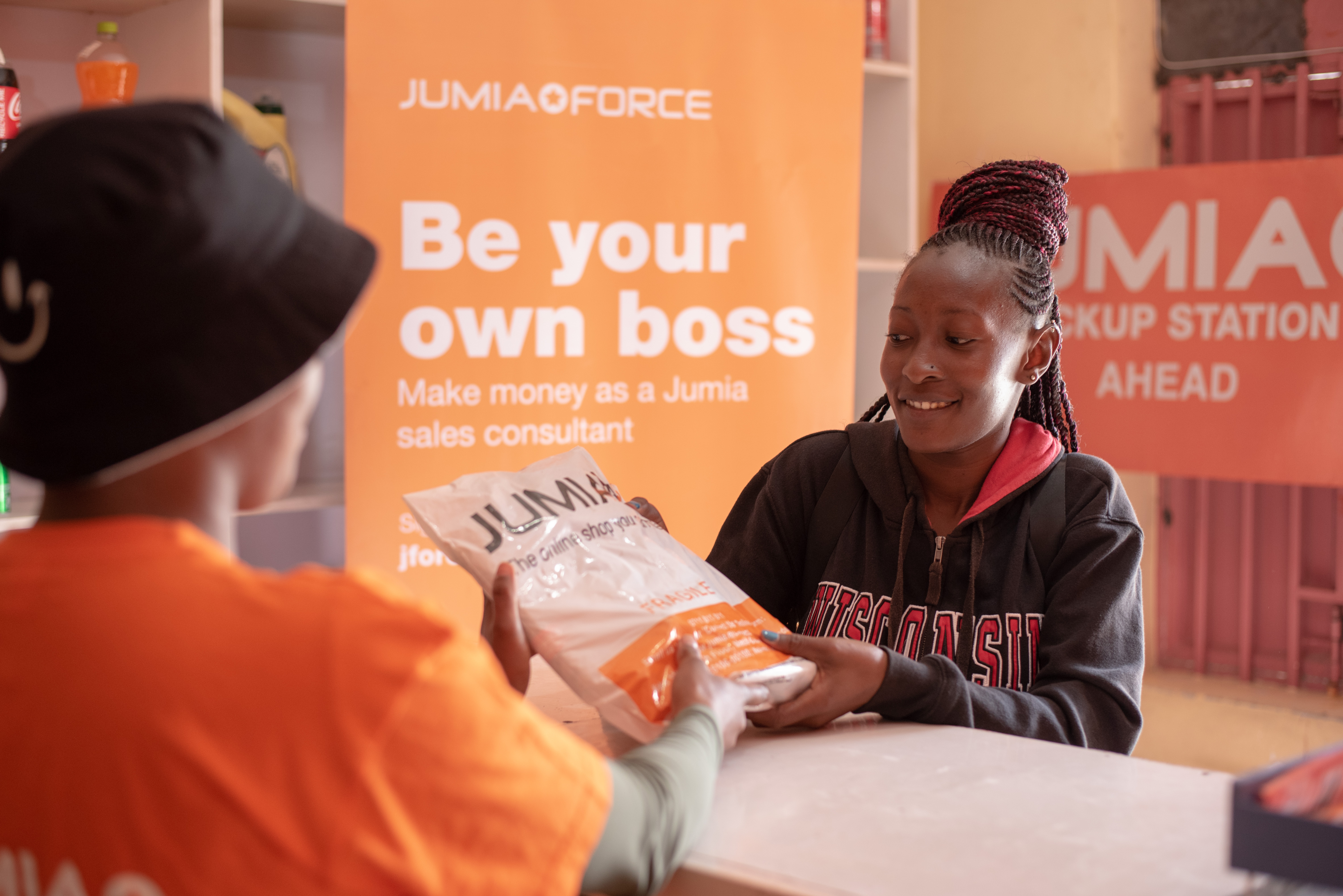 A JForce sales agent handing a Jumia package to a customer